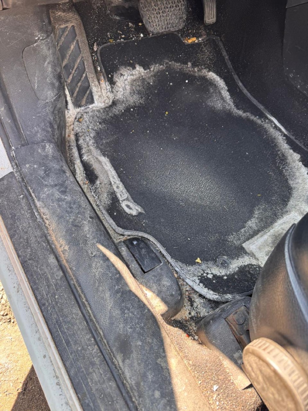 Car floor mat covered in white winter salt stains before, and clean footwell after salt removal — before